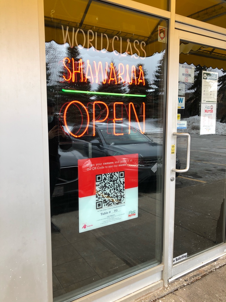 Open sign with visible QR code menu posted at the front of a restaurant. This shows guests that they can place their order without entering the restaurant.