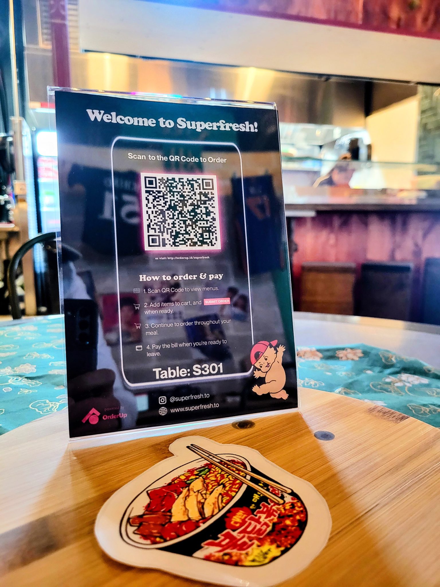 black background with a QR code outlined in neon pink and instructions below on how to order andpay from your phone. Superfresh Toronto Food hall logo on the bottom right hand corner. Superfresh uses orderup's contactless ordering and payment for their food hall